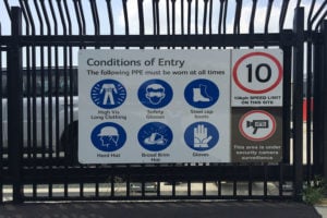white sign displaying blue icons indicating safety aspects of a work site